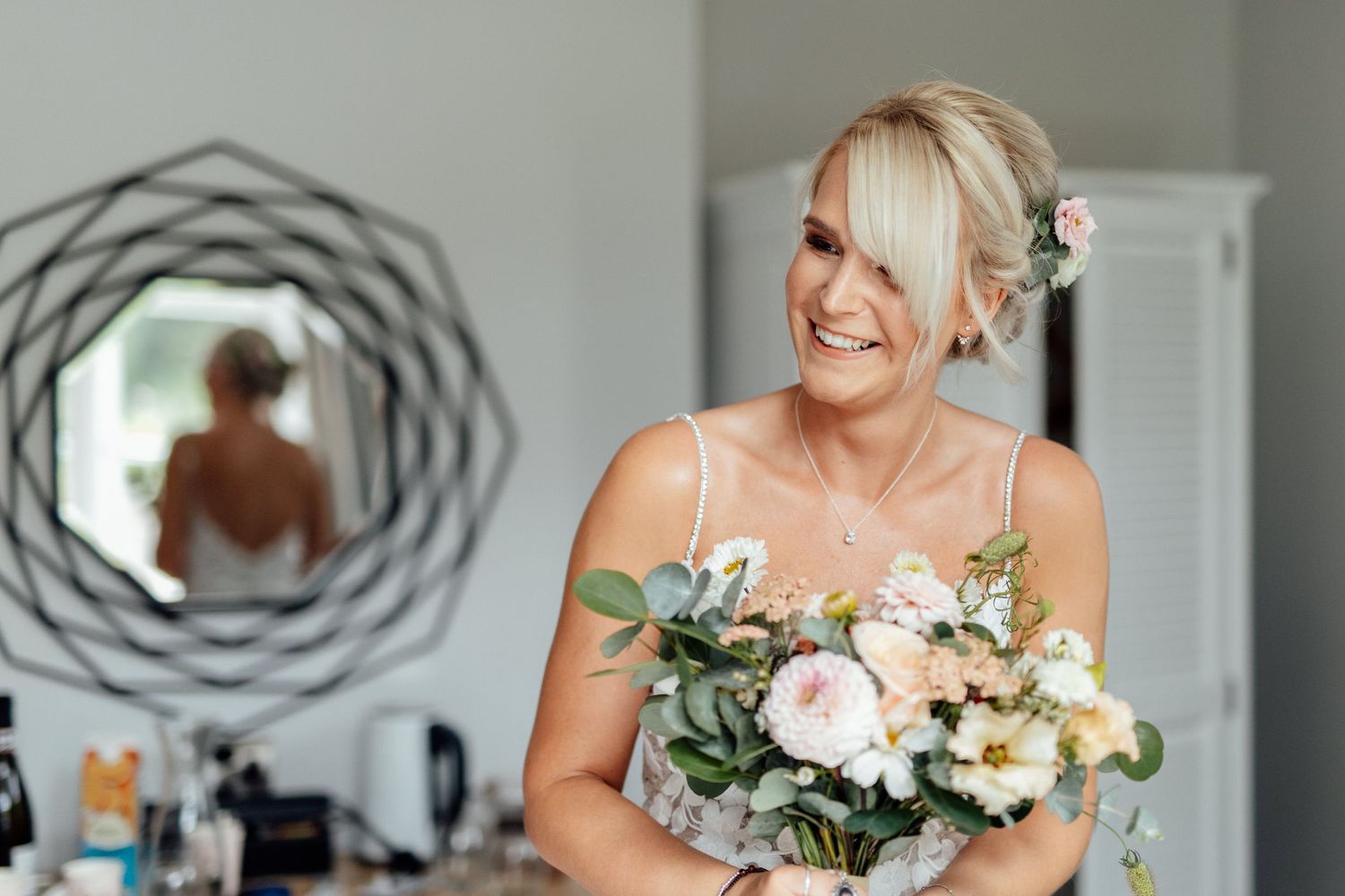 Beautiful wedding bouquet with blush roses and eucalyptus held against a white dress.