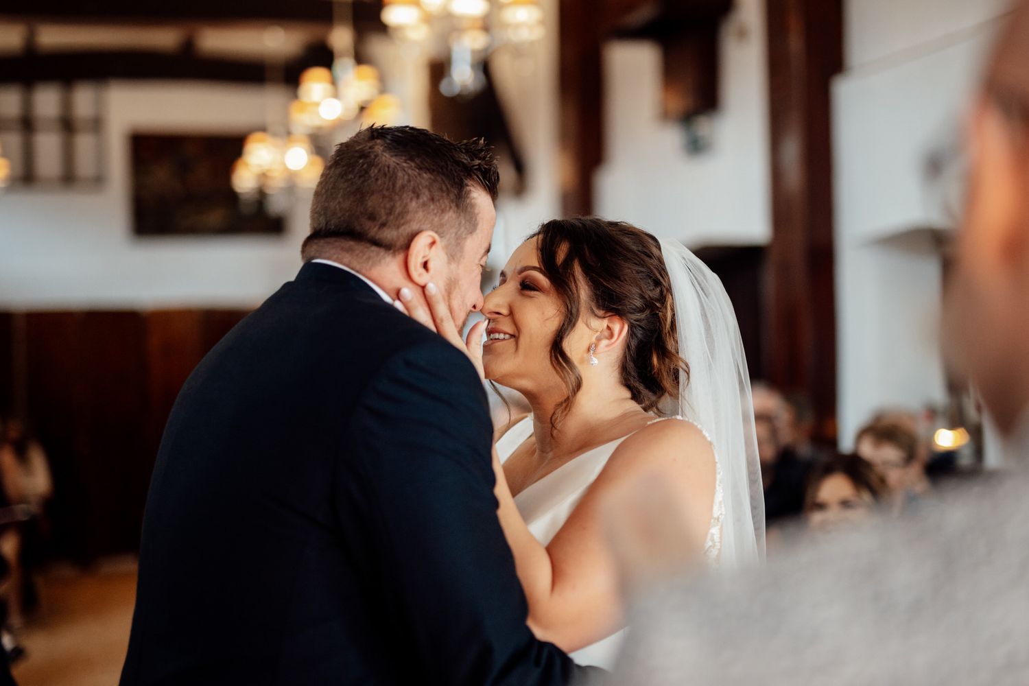 A romantic wedding couple shares intimate moments in an elegant indoor venue.