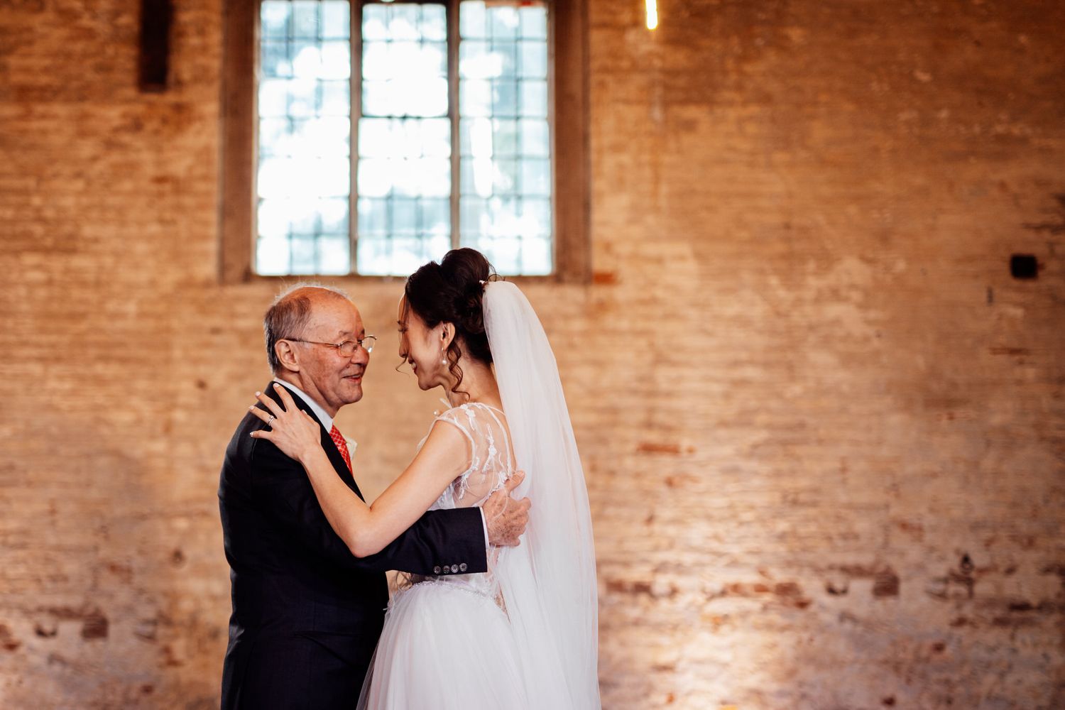 Intimate wedding ceremony moments in a historic brick venue with natural light streaming through windows.