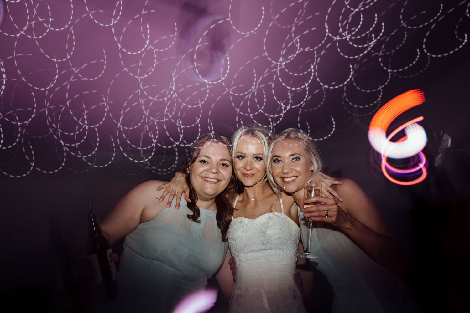 Wedding celebration with purple mood lighting and string light decorations overhead.