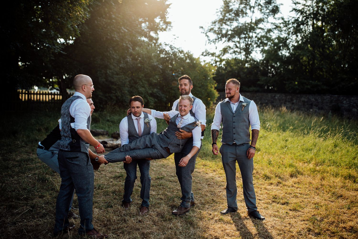 Wedding party enjoying candid moments together in golden sunset light.