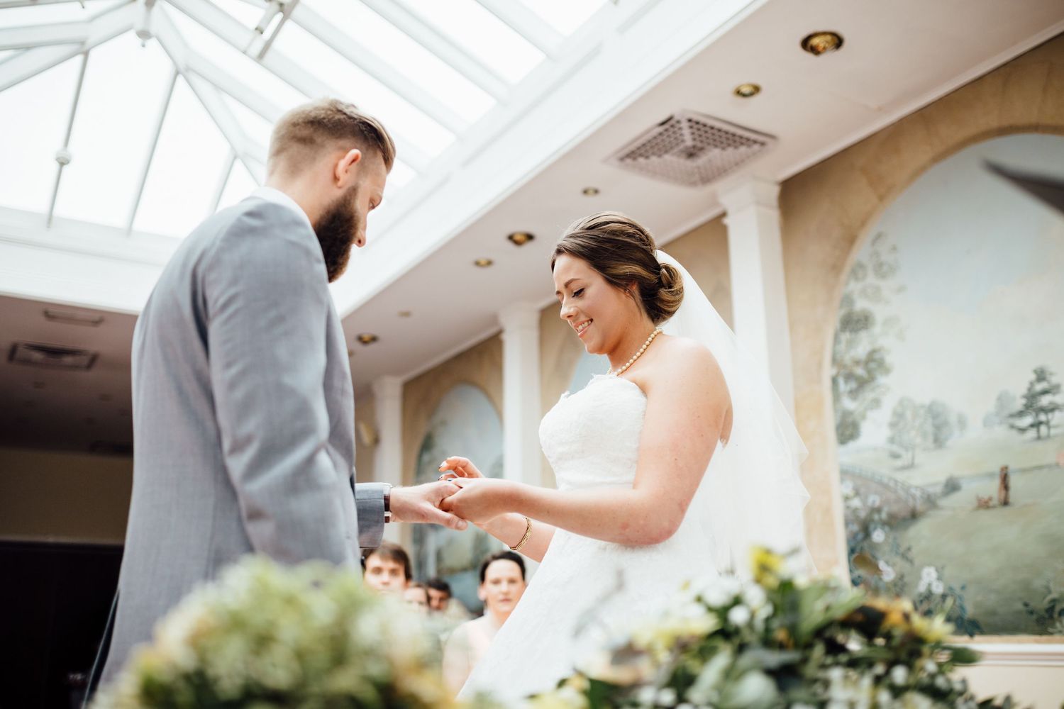Wedding ceremony in a bright conservatory room with white skylights and elegant decor.