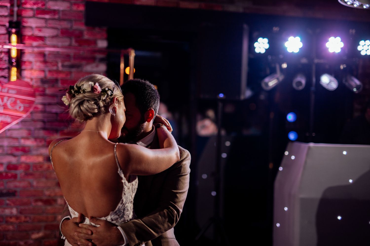 Romantic first dance at wedding reception with dramatic purple lighting.