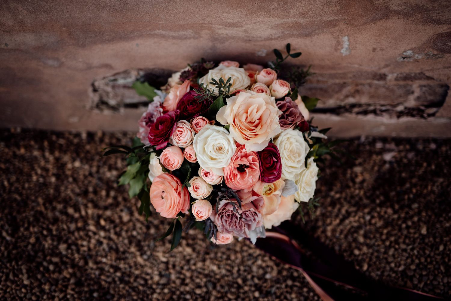 Beautiful coral and white wedding bouquets arranged on rustic stone surface.
