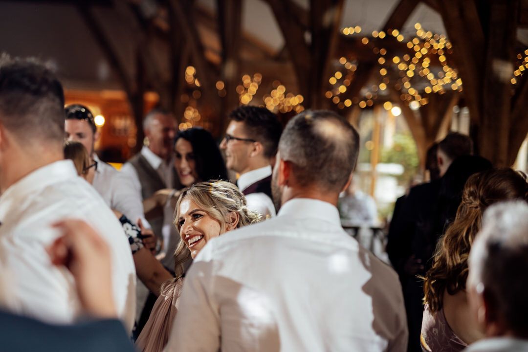 Wedding reception dance floor filled with celebrating guests under string lights.