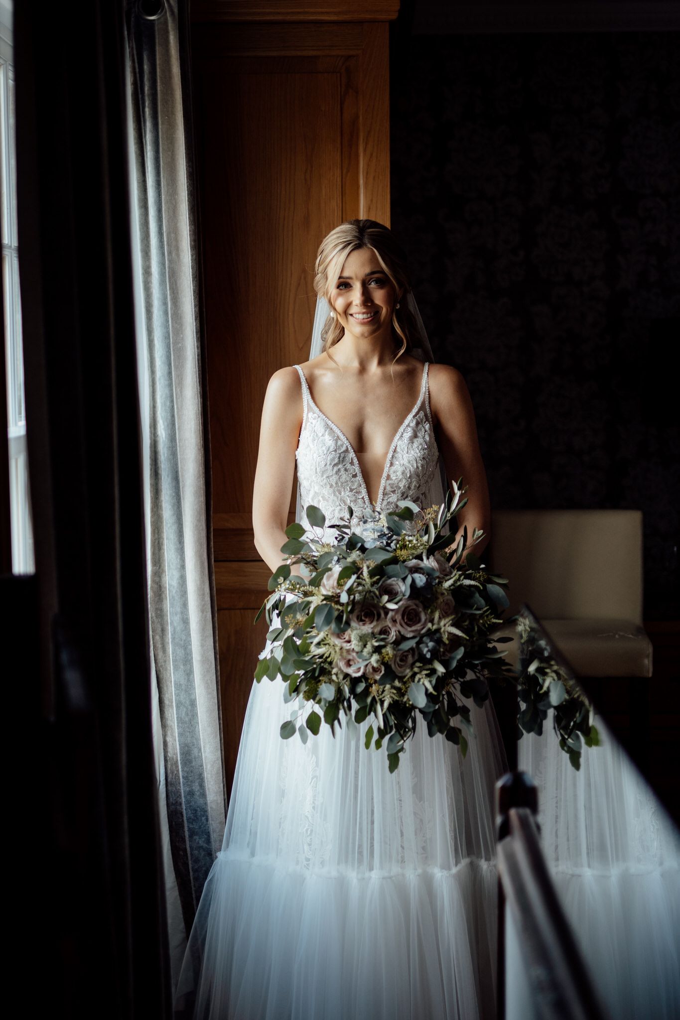 Elegant bridal portraits featuring a white tulle wedding dress with floral accents in moody lighting.
