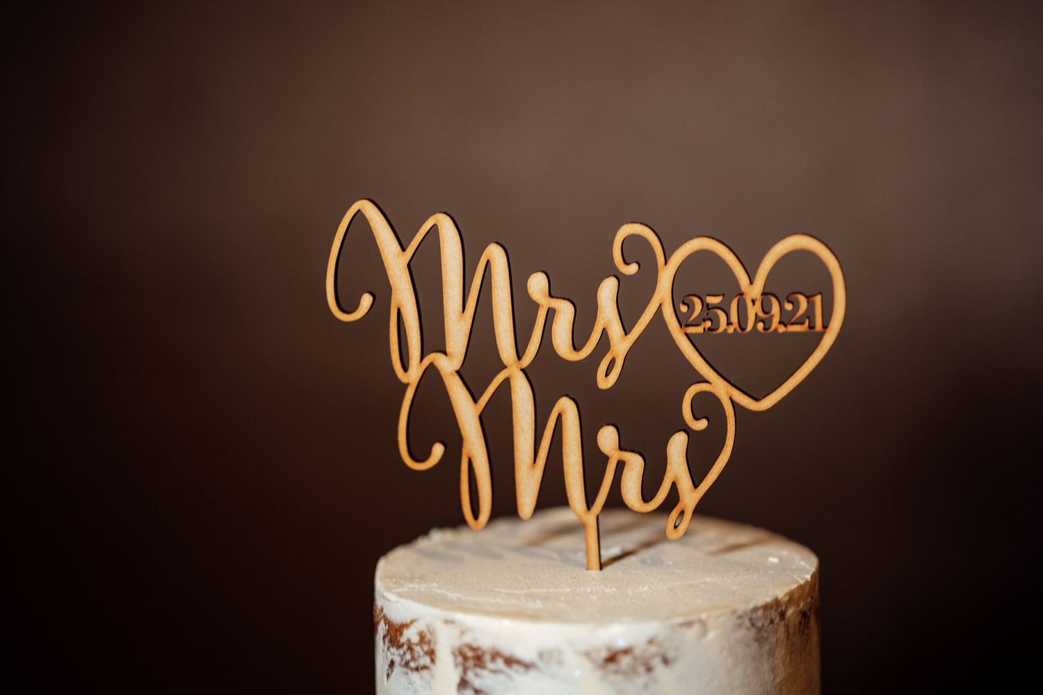Gold Mrs and Mrs wedding cake topper on a white frosted cake.