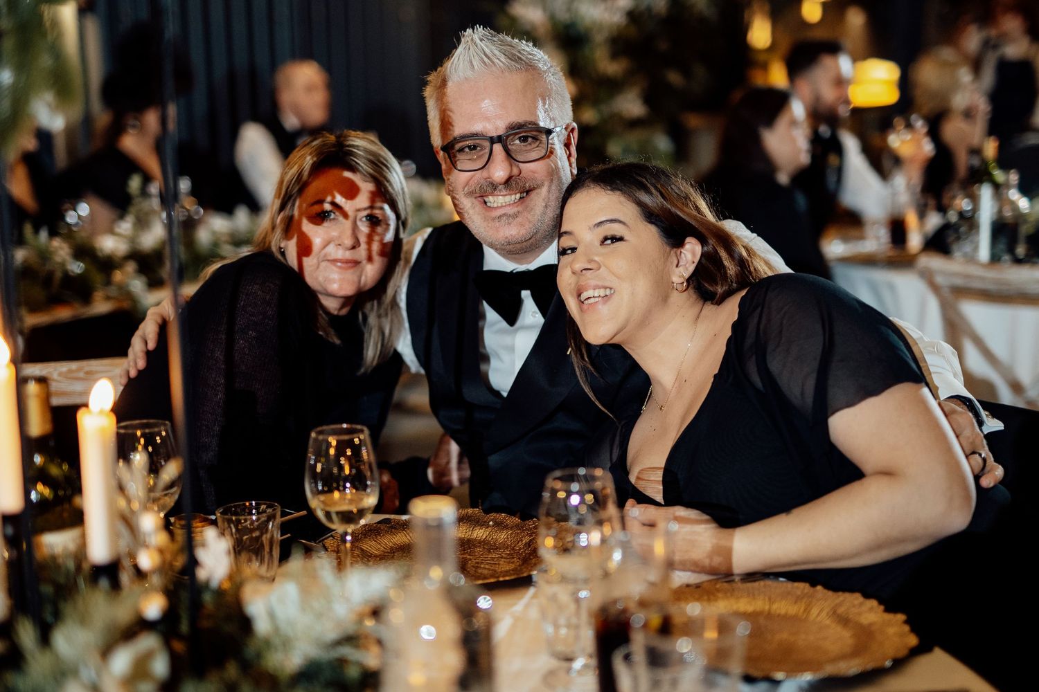 Wedding guests enjoy dinner and conversation at elegantly decorated reception tables.