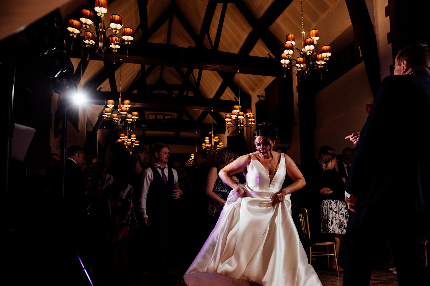 Wedding celebration in a rustic barn venue with chandelier lighting and wooden beams.