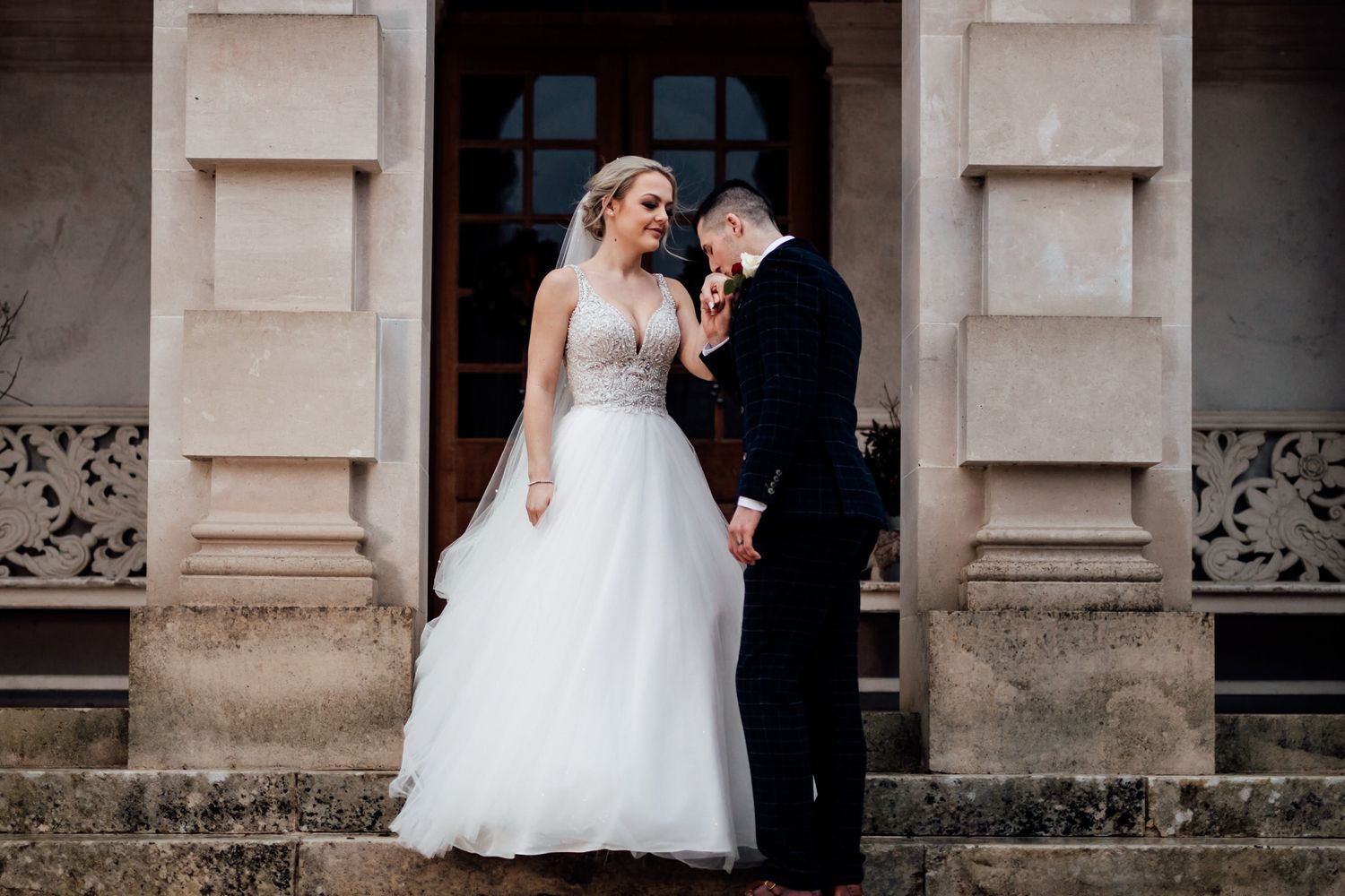 Wedding couple sharing moments outside a classical stone building entrance.