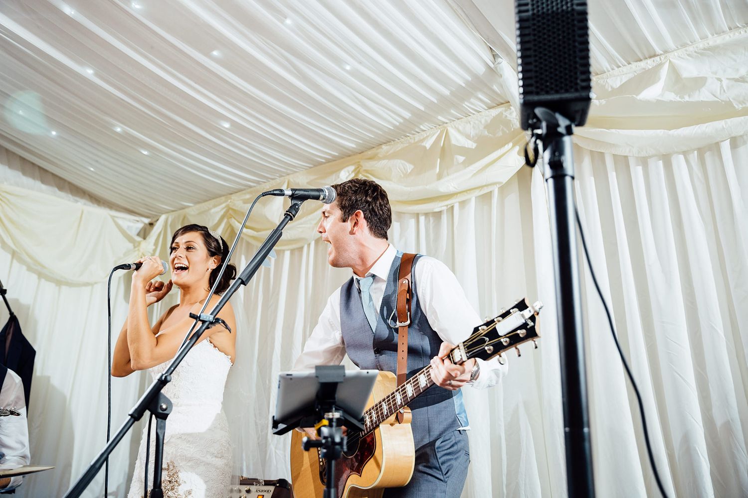 Musicians performing at a wedding reception under an elegant white tent.