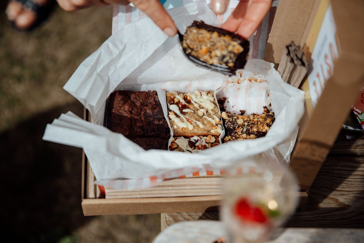 Close-up shots of chocolate chip cookies and brownies being served on white paper.
