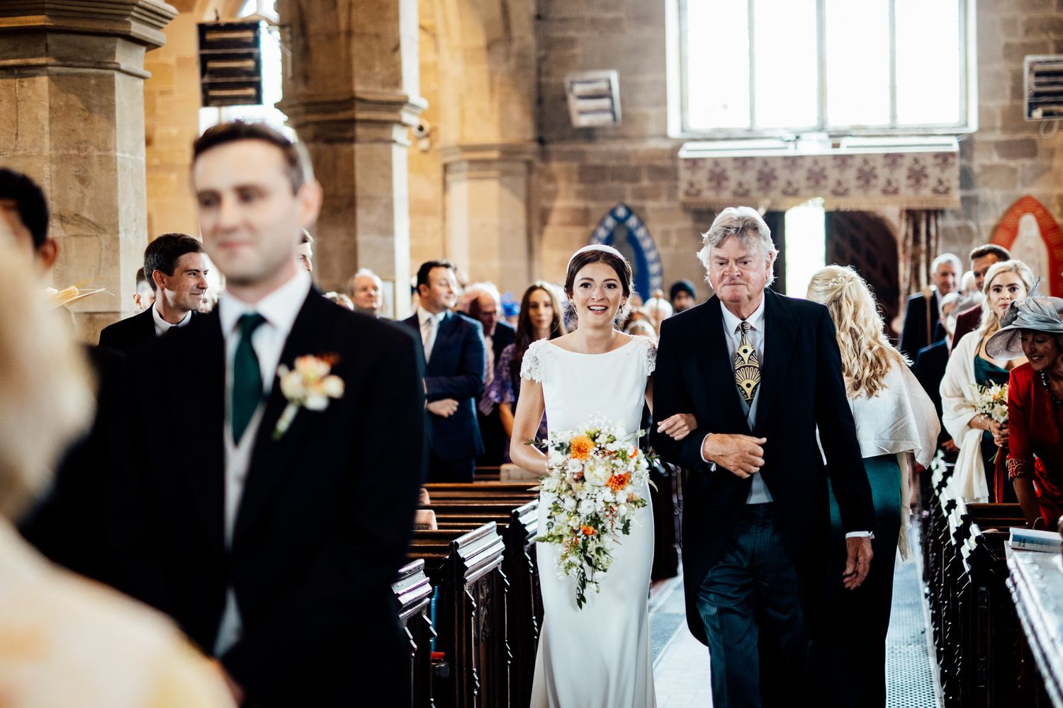 Wedding guests gathered in formal attire inside a traditional church sanctuary.