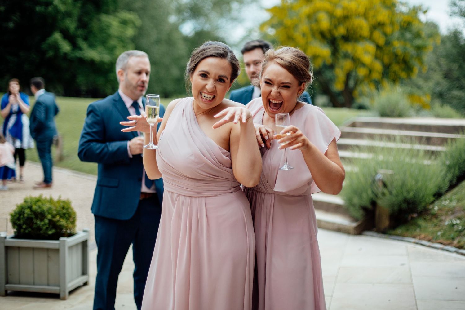 Bridesmaids in blush pink dresses laughing together outdoors.