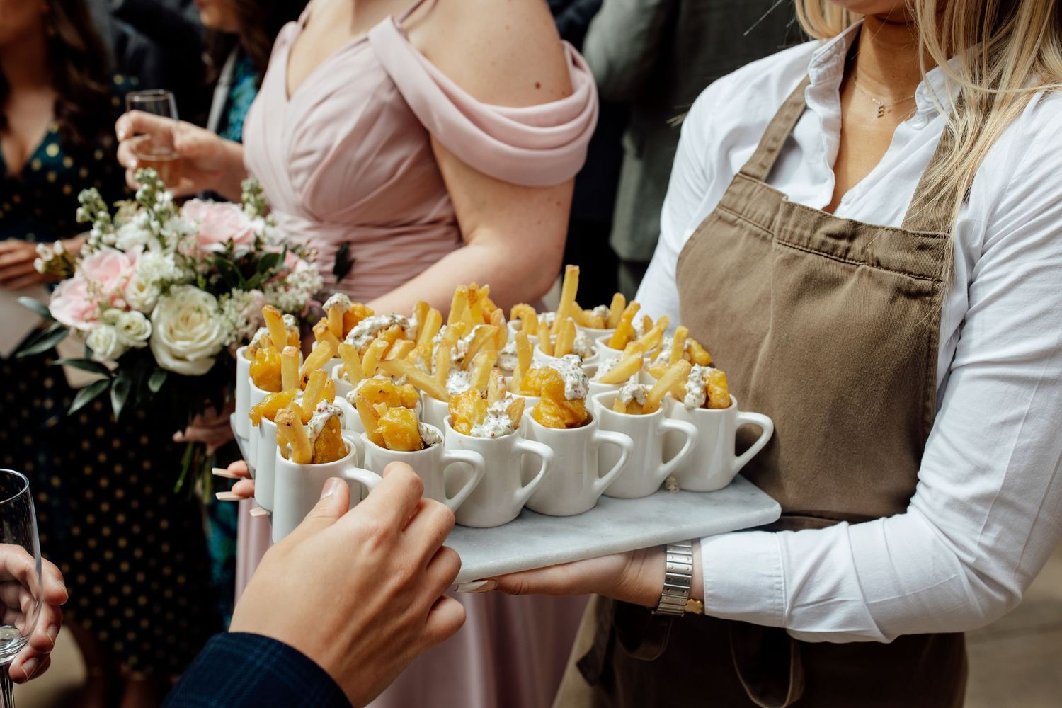 Servers present appetizers and drinks on trays during an elegant wedding reception.