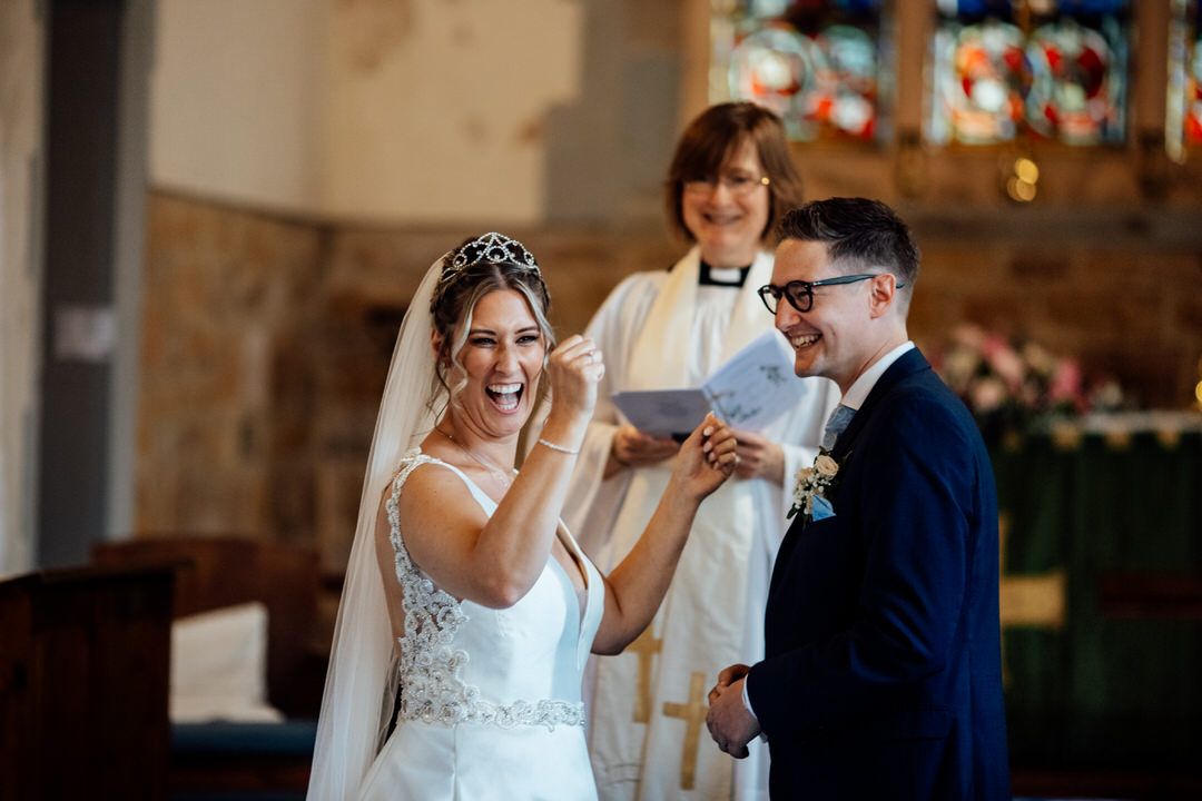 Joyful wedding ceremony moment captured in historic stone church.