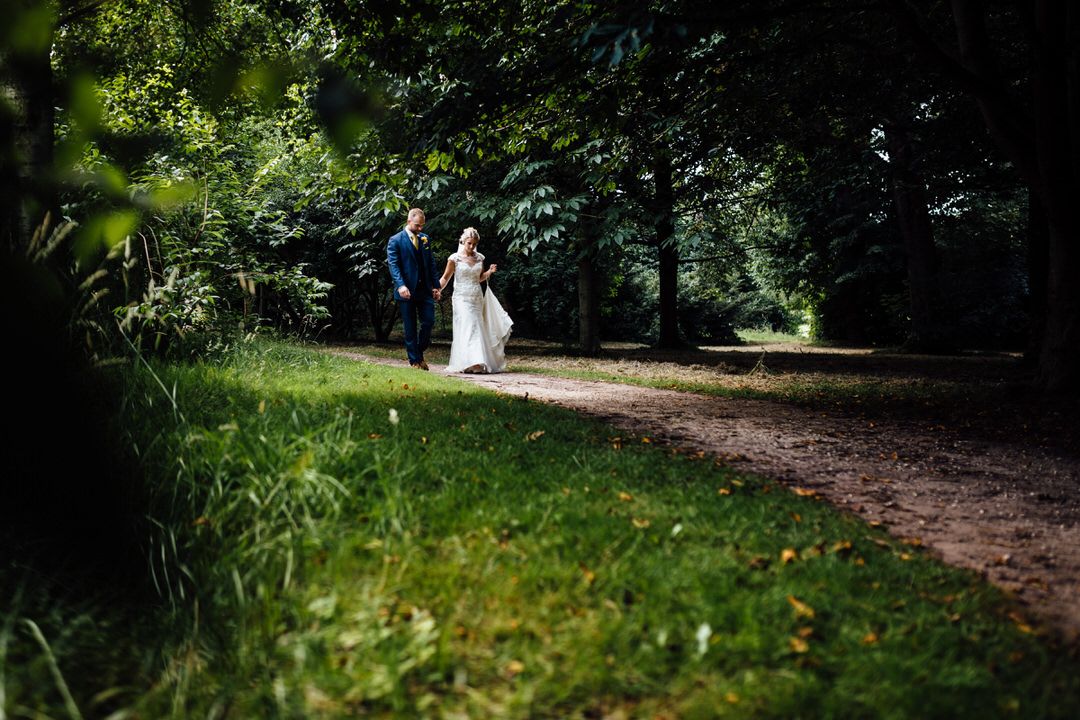 Wedding couple walking through a scenic garden path surrounded by greenery.