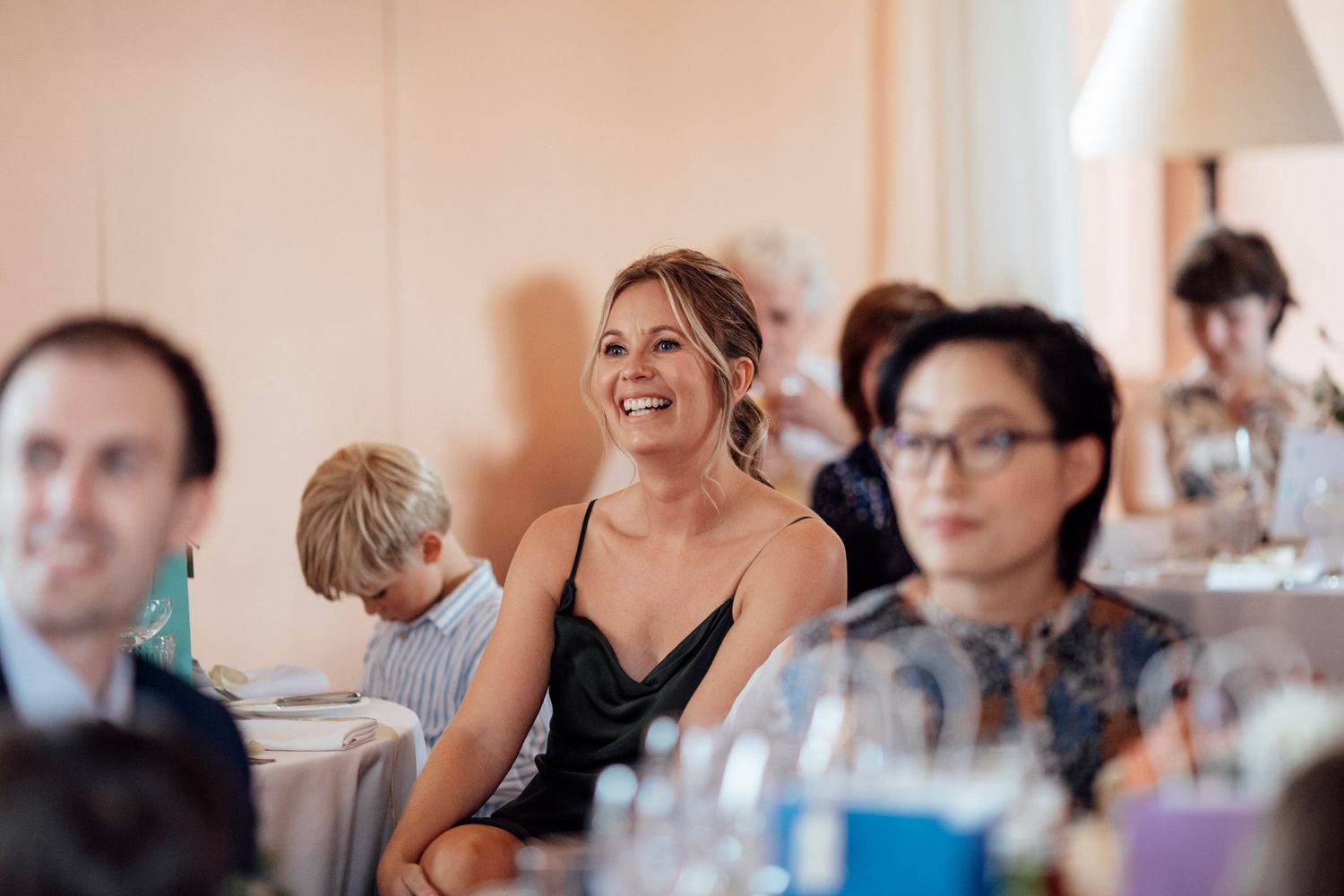 Wedding reception guests enjoying dinner at tables with glassware.