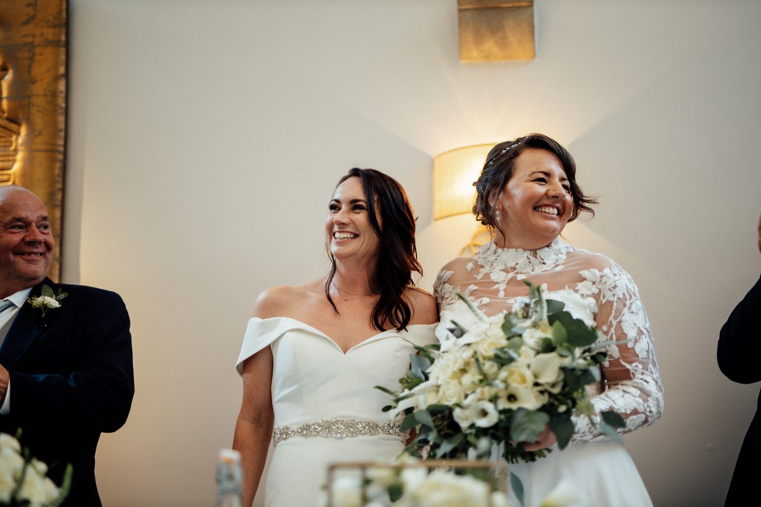 Happy couple laughing during their wedding ceremony with white floral bouquet.