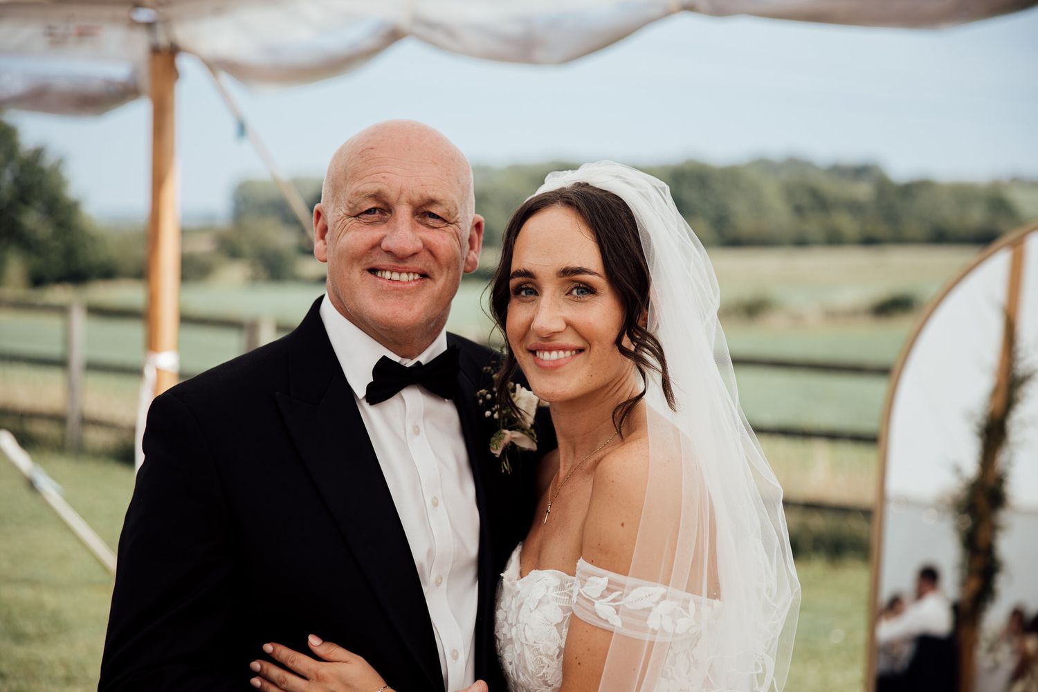 Outdoor wedding celebration under blue skies with elegant white decor and floral arrangements.