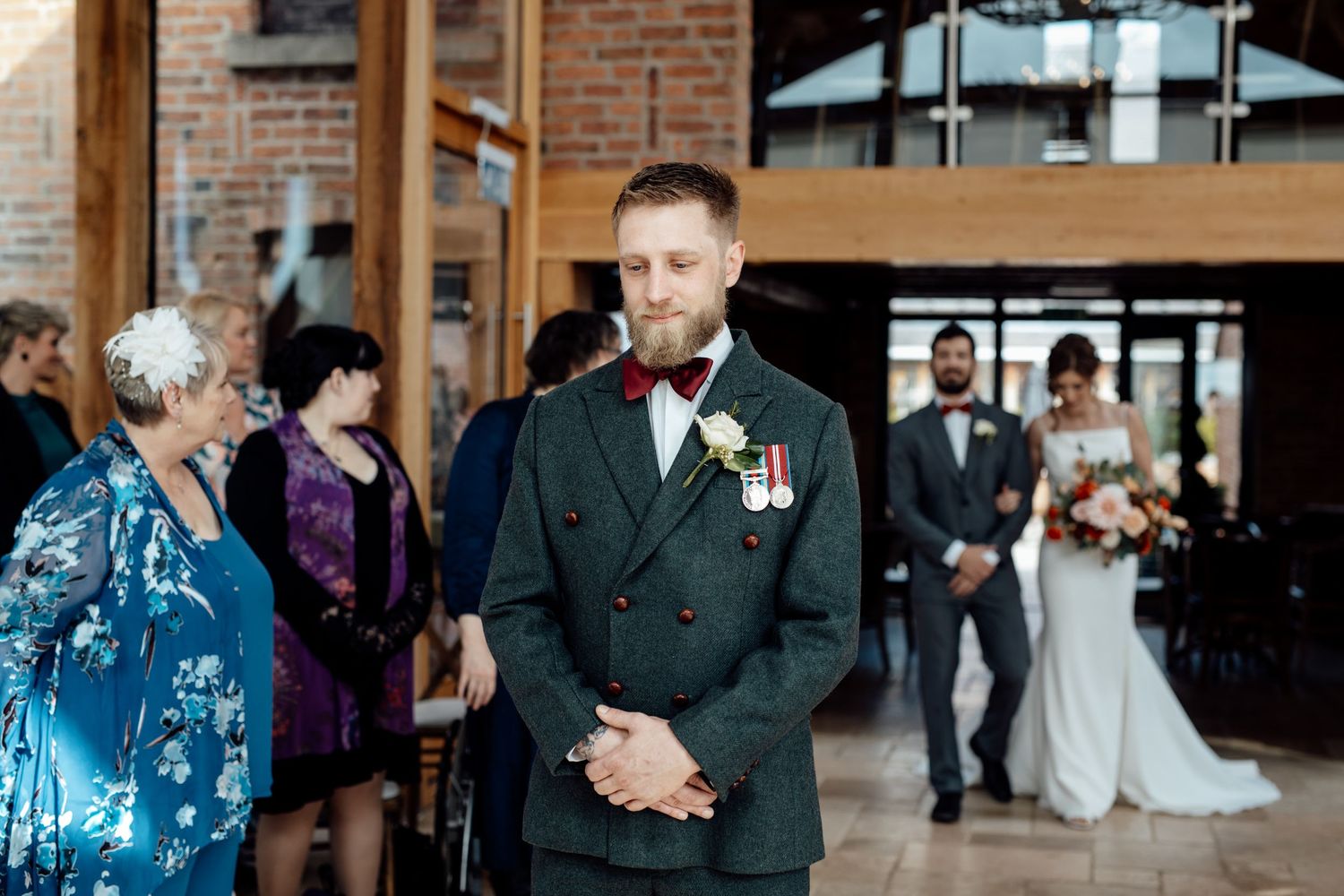 Wedding ceremony in a rustic brick venue with natural light streaming through large windows.