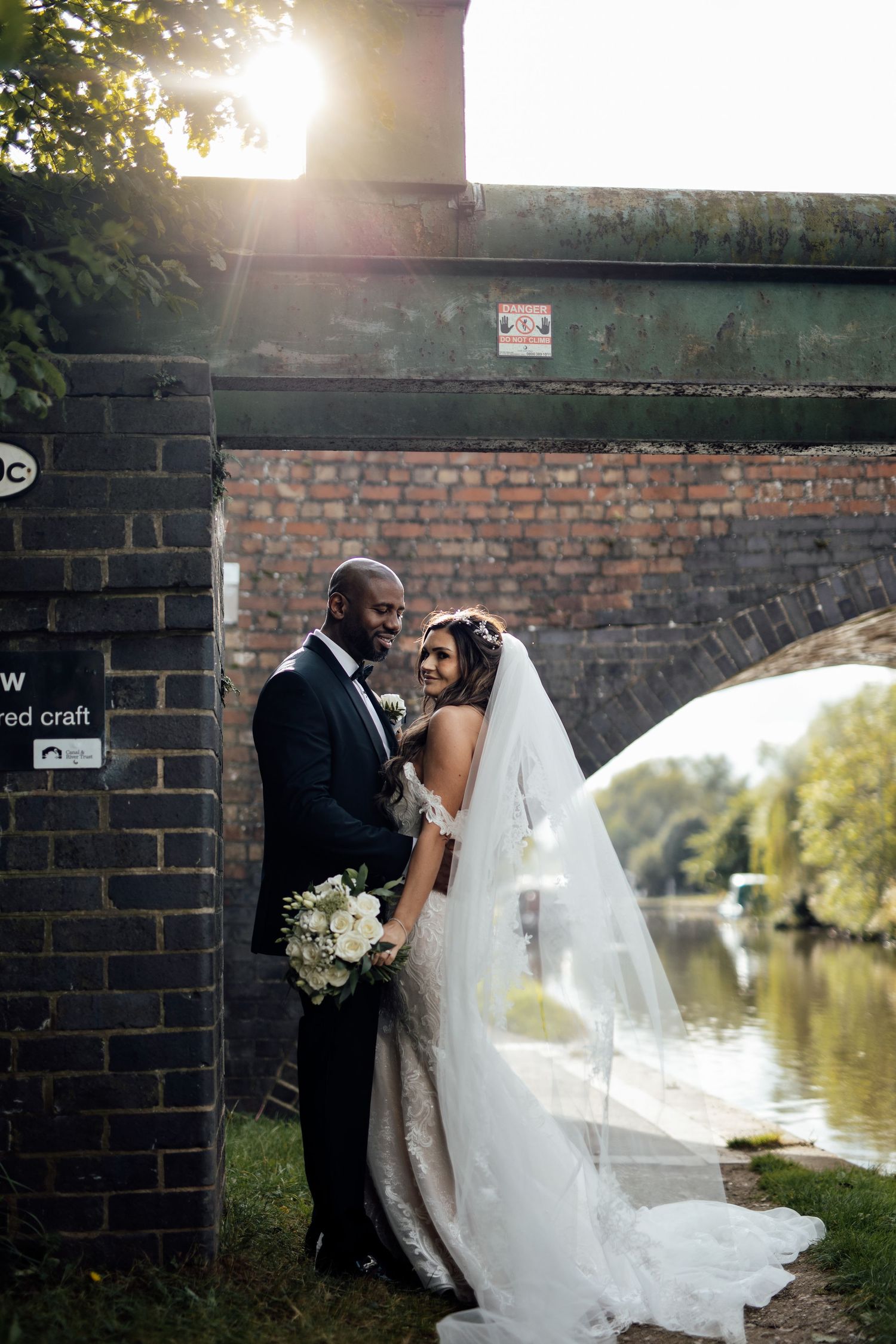 Couple sharing an intimate moment by a brick wall near a waterfront.