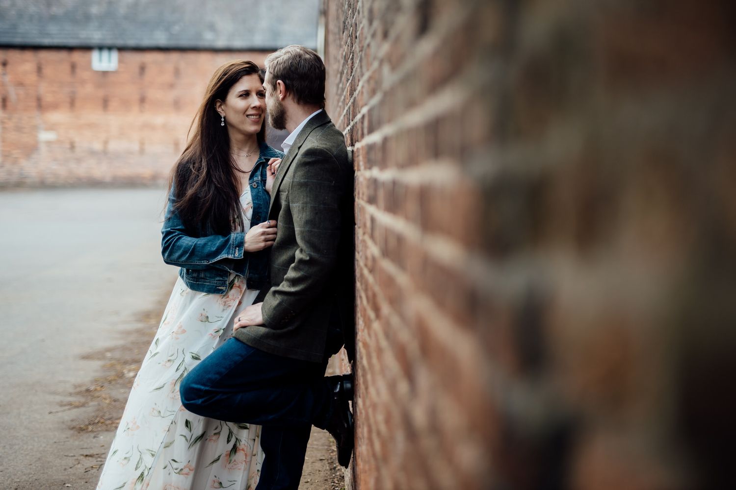 A couple embraces against weathered brick walls during a photo session.