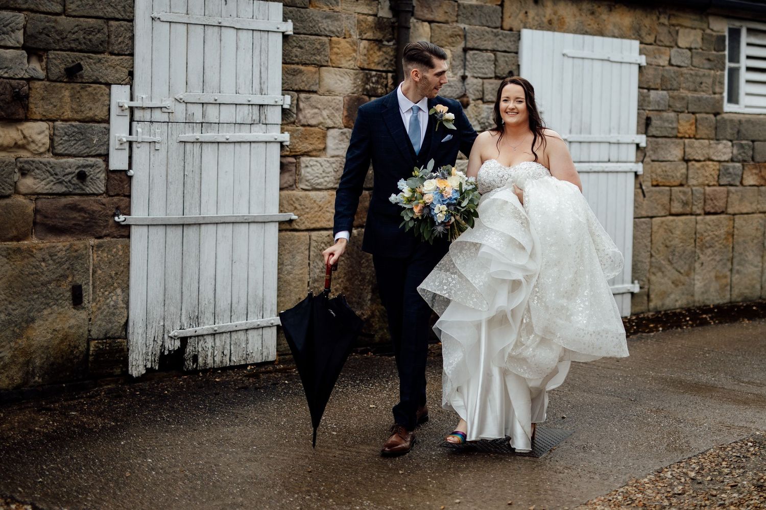Stone wall backdrop with white door creates rustic setting for wedding photography.