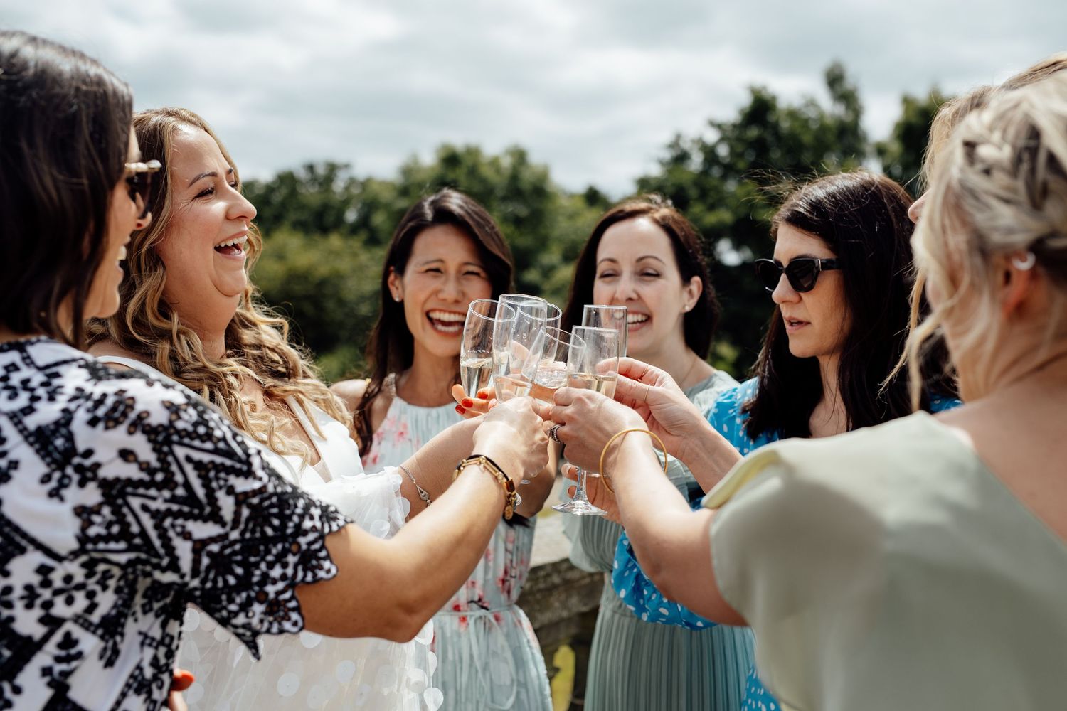 Wedding celebration with guests toasting and laughing together outdoors.
