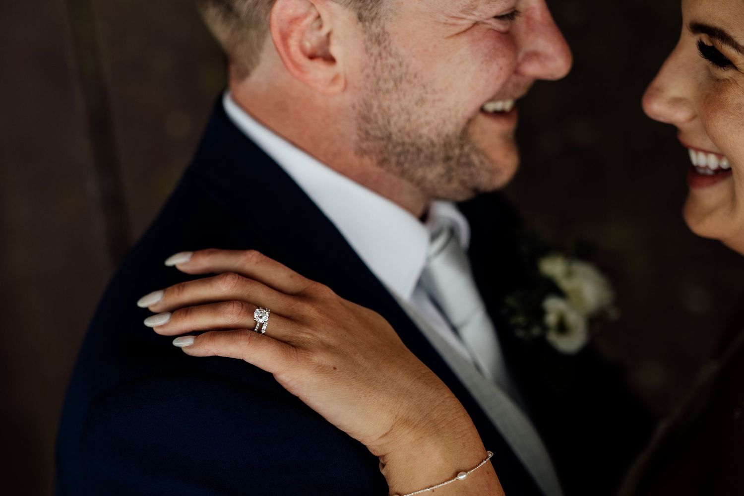 Close-up romantic moment with engagement ring visible in soft lighting.