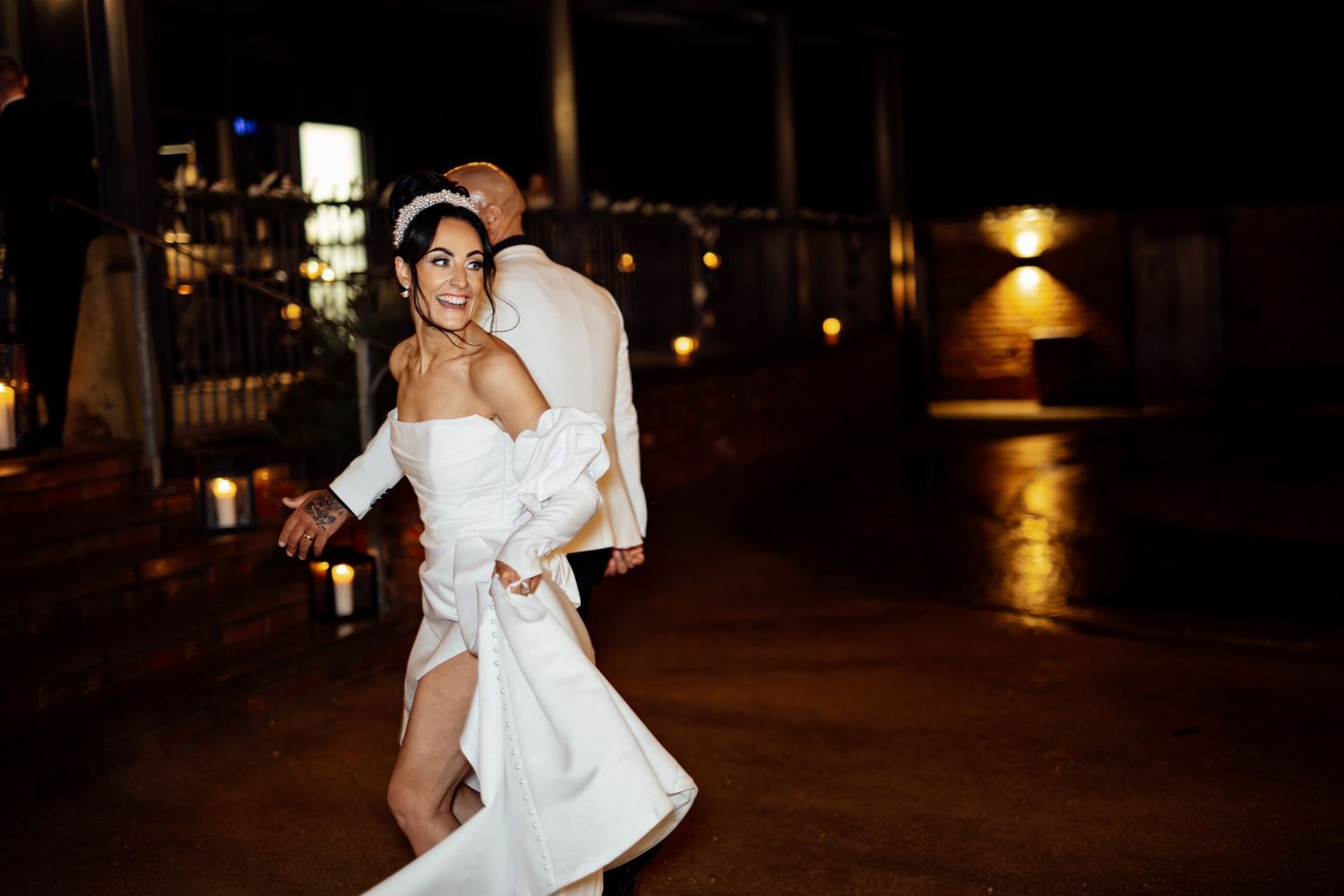 Couple dancing together under string lights at an outdoor evening celebration.