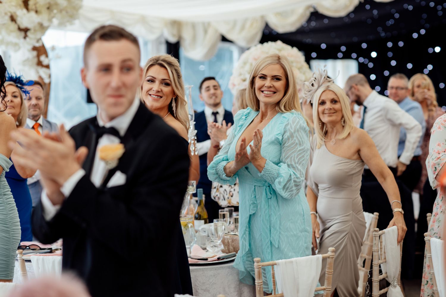 Wedding reception guests celebrate with joyful expressions under sparkling lights.