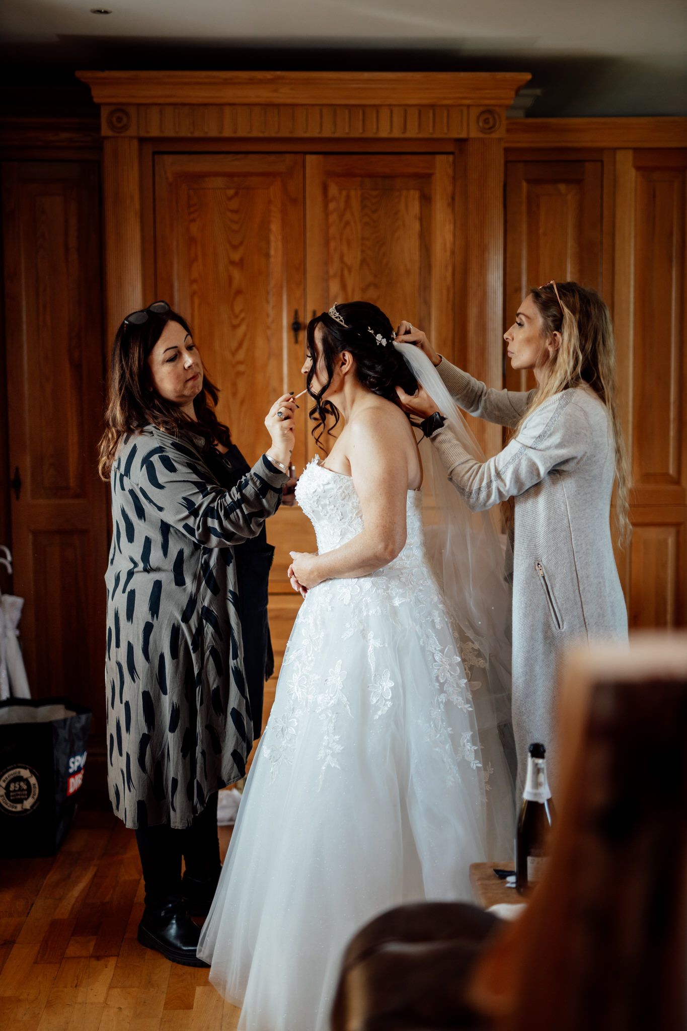 Wedding preparation scene in a wood-paneled room with elegant white gowns.