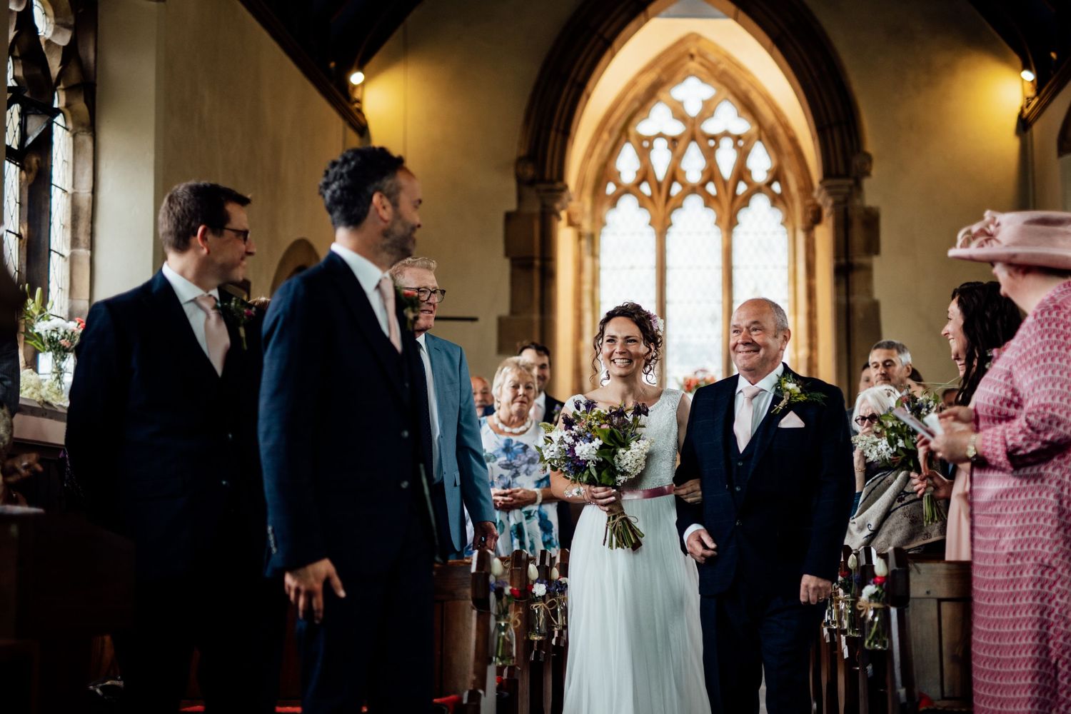 Wedding ceremony taking place inside a historic church with gothic architecture and stained glass windows.
