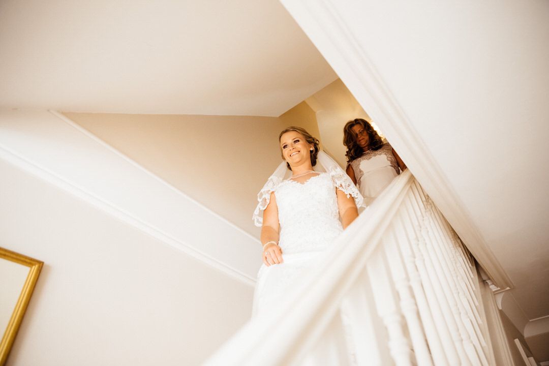 A white wedding dress hangs elegantly against a neutral wall.