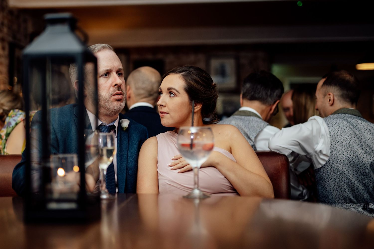 Wedding reception guests mingling in a dimly lit venue.