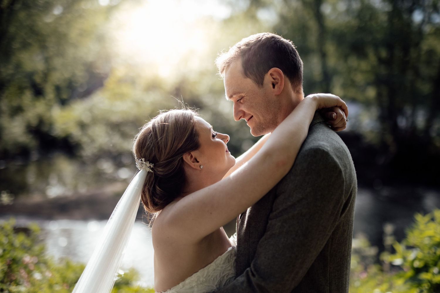 Romantic outdoor wedding portraits with couples embracing against natural sunlit backdrop.