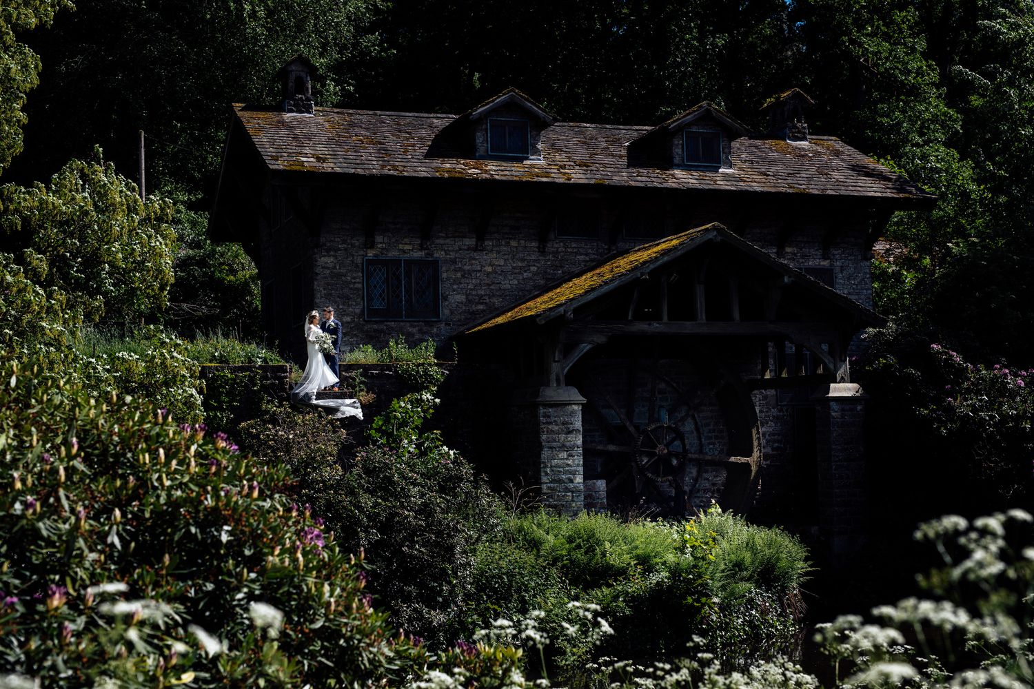 Scenic outdoor wedding venue nestled among lush greenery and stone buildings.