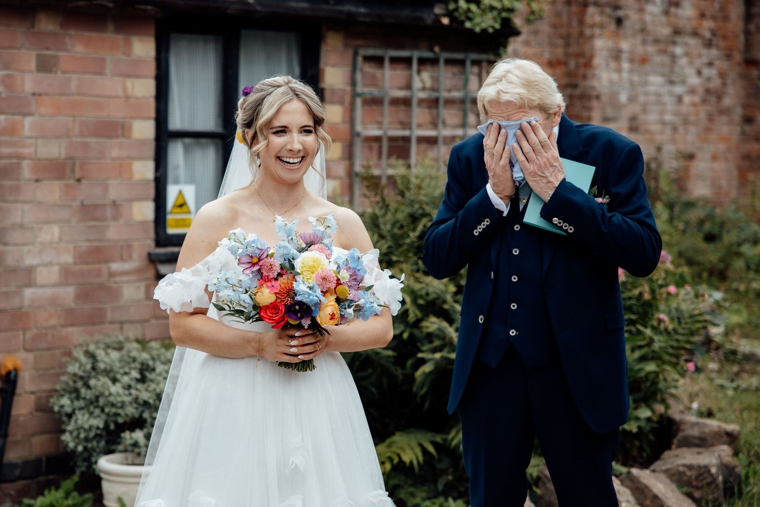 Candid wedding moments captured outside brick building with floral bouquets.