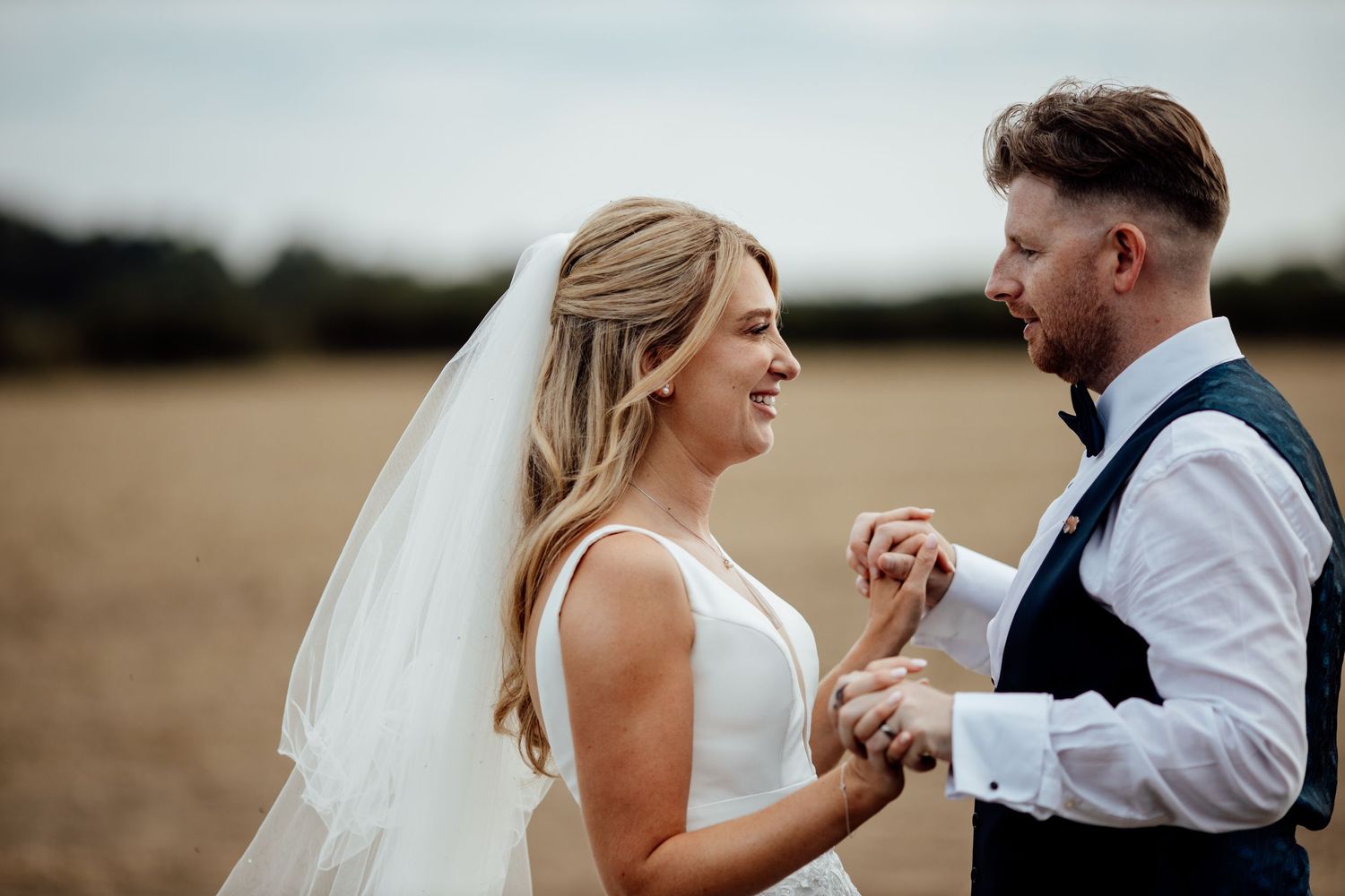 Couple sharing an intimate moment during their wedding photoshoot in a field at golden hour.