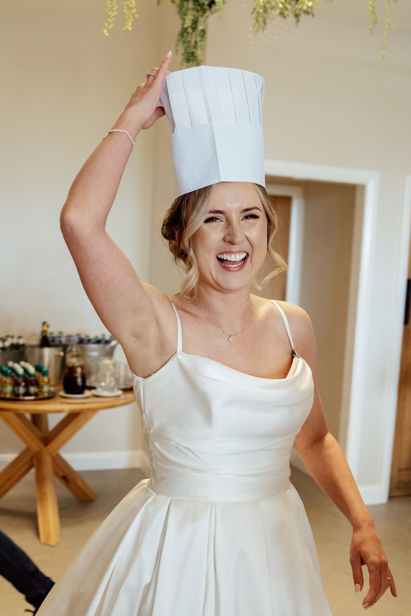 A playful moment as someone poses in a white wedding dress with a chef's hat.