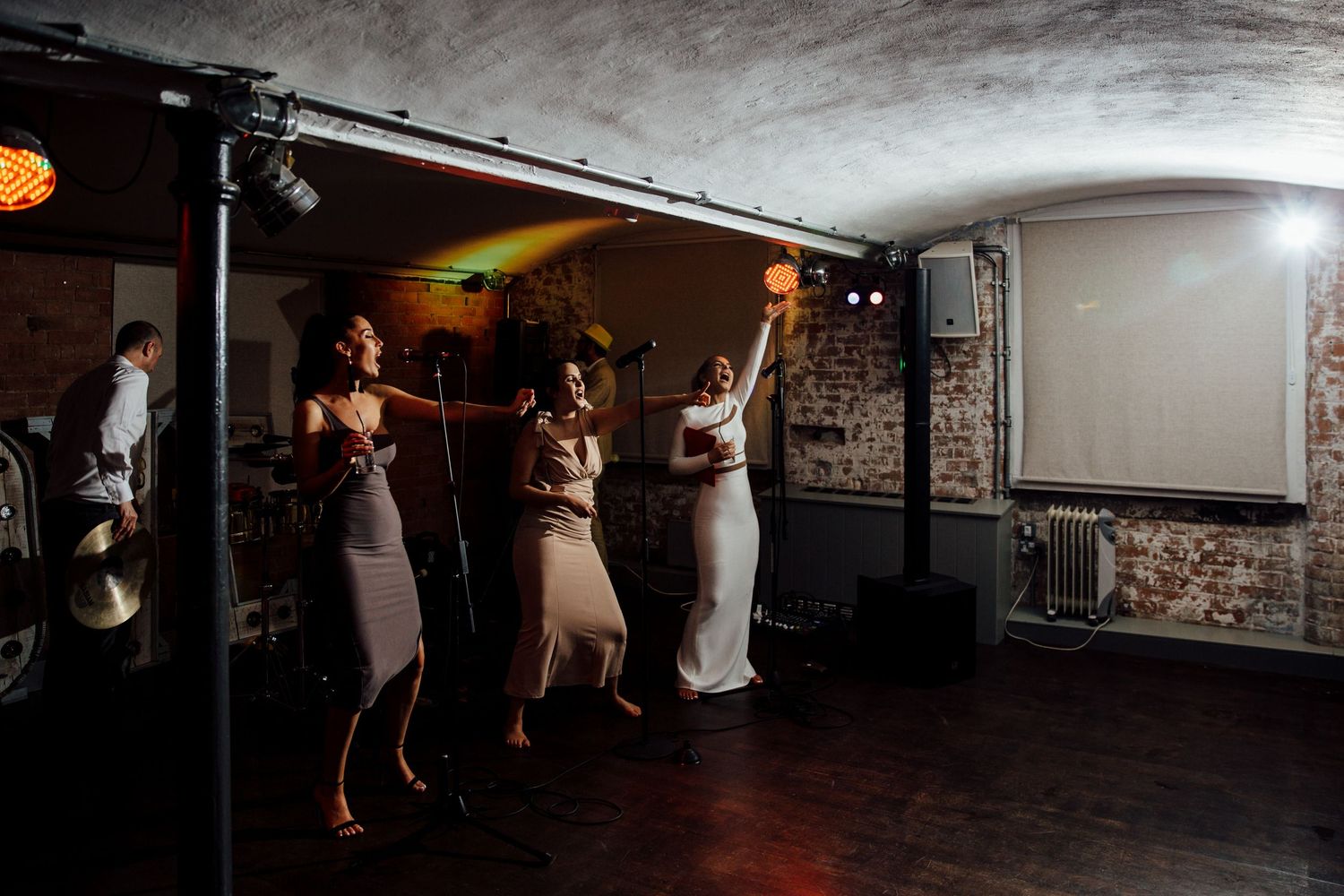 Wedding guests dancing and celebrating in a dimly lit reception space.