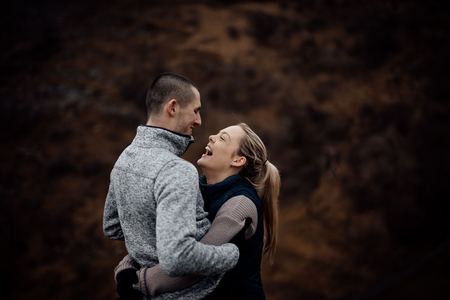 Couple embracing against a rugged natural backdrop.