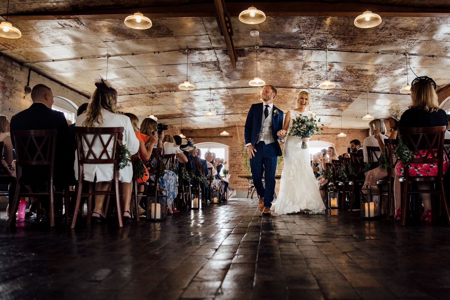 Wide angle view of a reception venue with pendant lights and wooden floors.