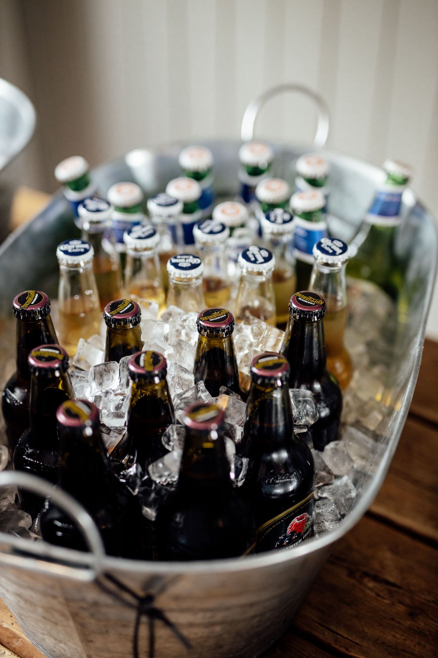 Glass bottles of beer and drinks chilling in ice buckets on a rustic wooden table.