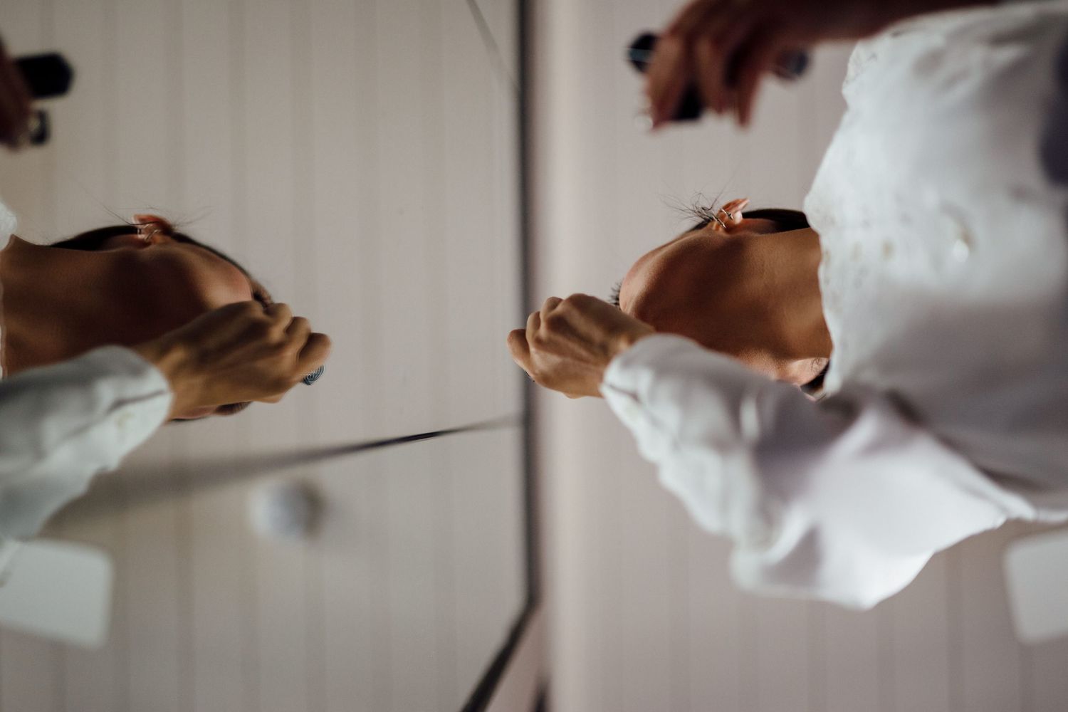 Close-up of hands adjusting formal white shirt cuffs in mirror reflection.