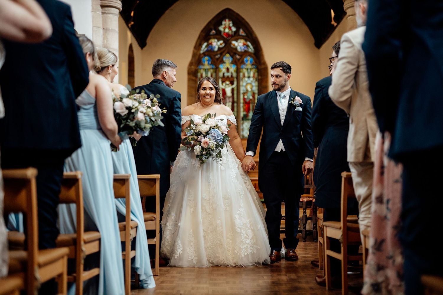 Wedding ceremony taking place inside a traditional church with gothic arches and wooden pews.