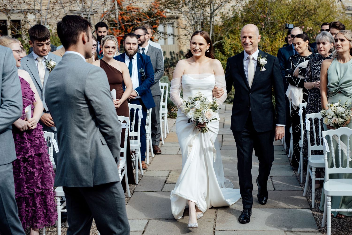 Wedding ceremony guests walking along stone pathway during outdoor celebration.