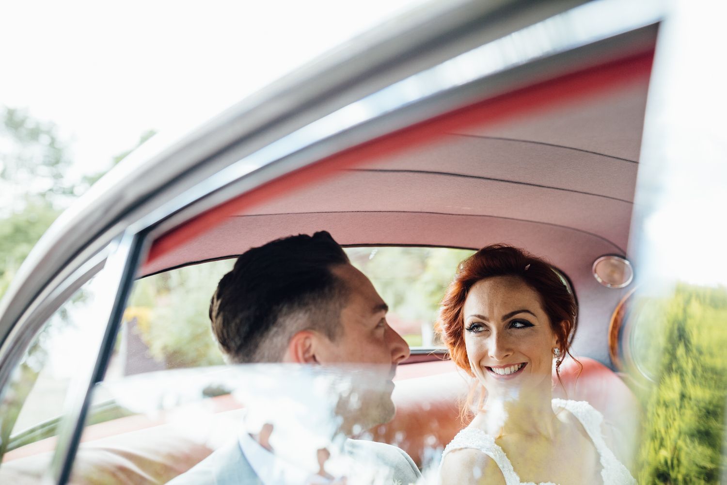 Newlyweds share a moment in a classic car after their wedding ceremony.