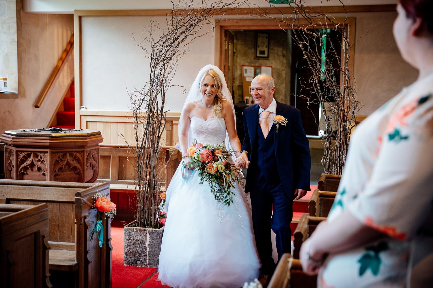 Wedding party poses inside an elegant venue with rustic branch decorations.